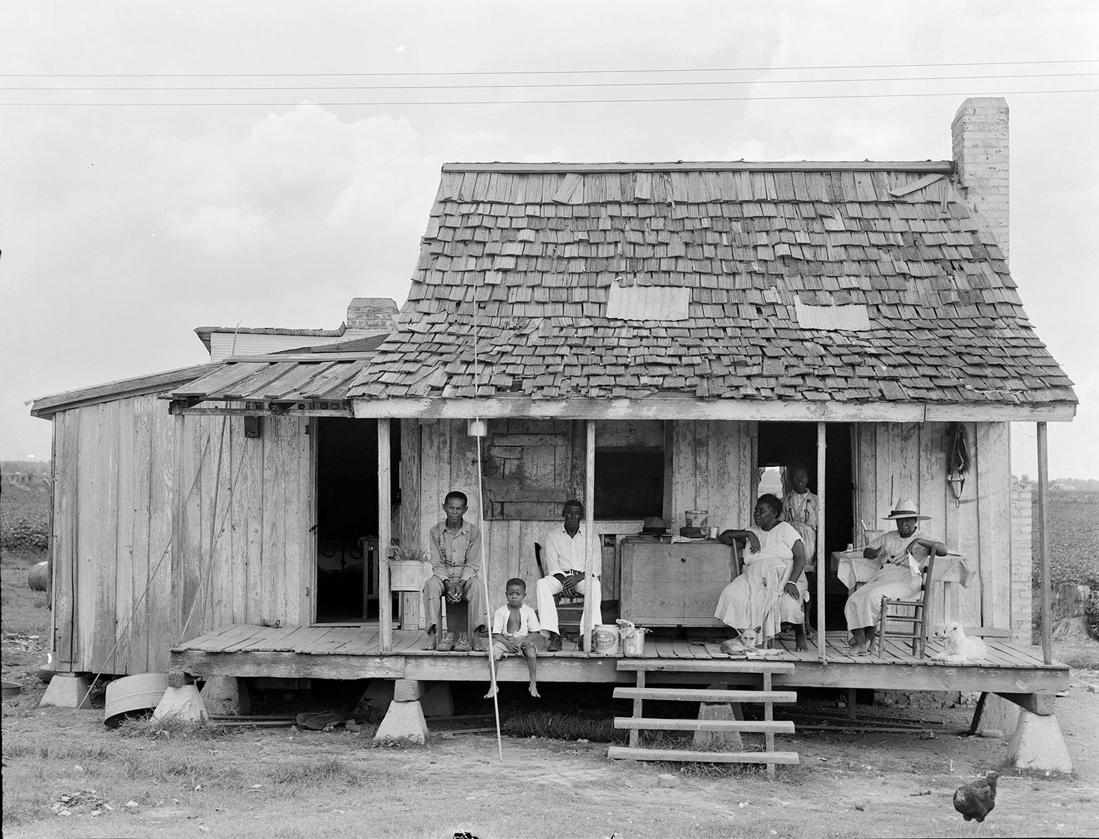 A photo of a family on a front porch on an Arkansas delta plantation, taken by Dorothea Lange in 1938.