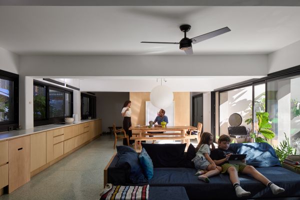 An open kitchen, dining, and living area, plus a powder room, takes up the entire ground level, which was previously a garage. The cabinetry is made of Ambay plywood, and the floor is poured terrazzo.