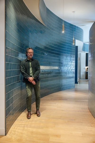 Lead architect Brock James leans against the curved hallway on the first floor. Lined in blue tiles, it represents the flow of water, a symbol of healing and life in Indigenous culture.
