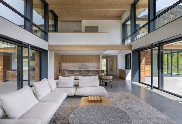 The kitchen sits beneath the open mezzanine level. Additional bedrooms are enclosed on this upper level, giving them a cozy, private feeling.