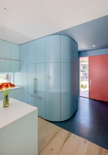 The red-tiled entrance leads past a set of curvaceous powder-blue cabinets to the kitchen.